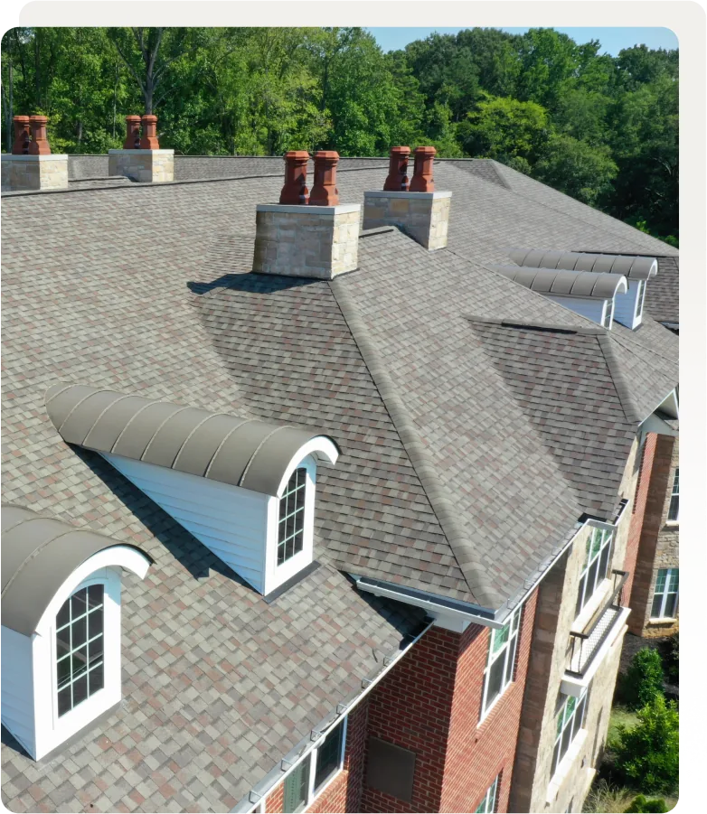 Gray shingle roof with brick chimneys and barrel dormers