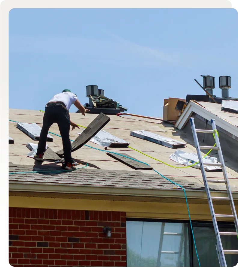 Roofer installing shingles from a ladder